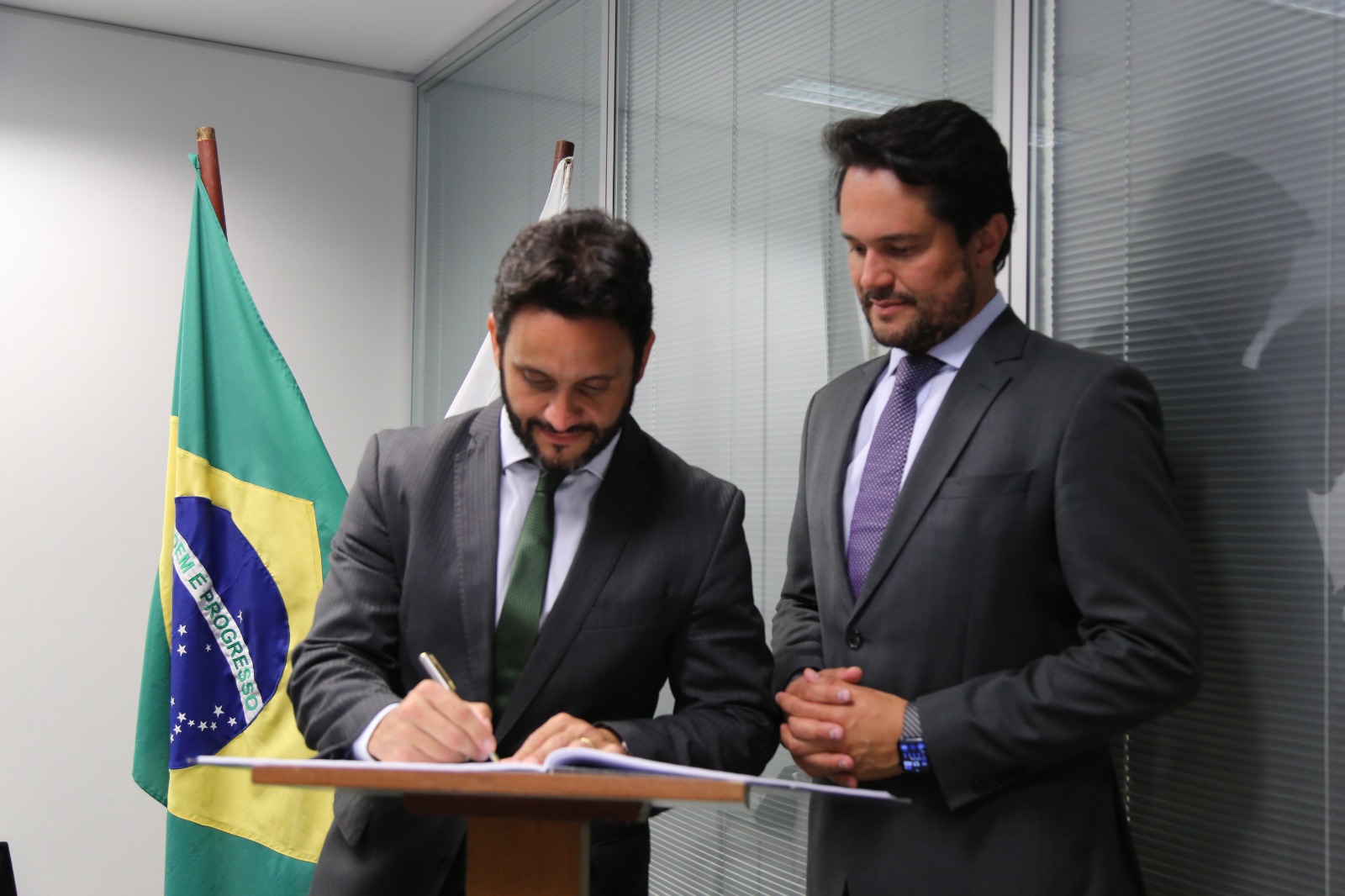 Thiago Toscano, à esquerda, assina a formalização das ações, acompanhado do secretário de Estado de Desenvolvimento Econômico, Fernando Passalio. 